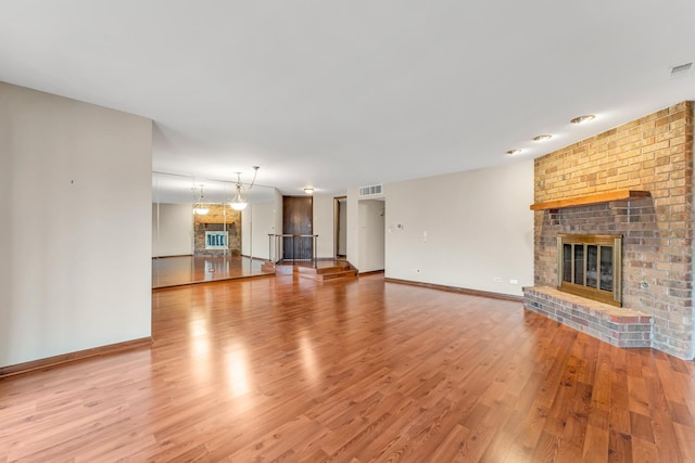 unfurnished living room featuring a brick fireplace and light wood-type flooring