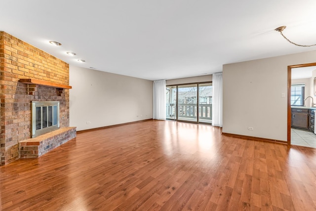 unfurnished living room with plenty of natural light, a brick fireplace, and light hardwood / wood-style flooring