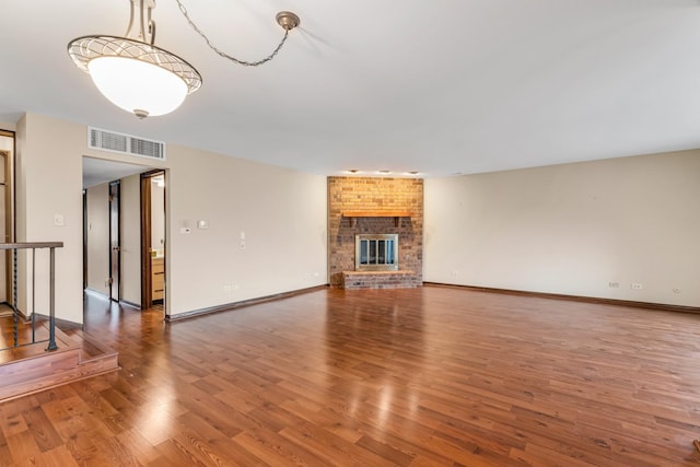 unfurnished living room with hardwood / wood-style flooring and a brick fireplace