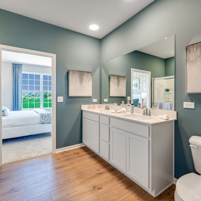 bathroom featuring wood-type flooring, toilet, a shower with door, and vanity