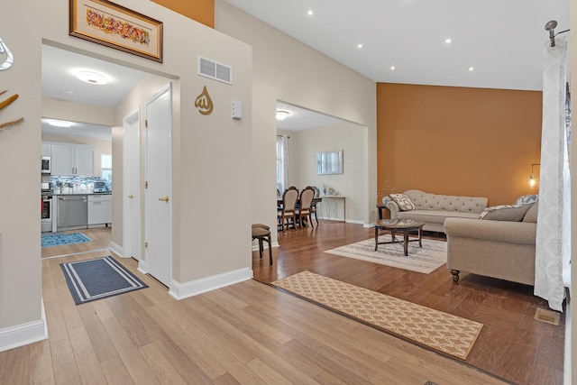 corridor with a towering ceiling and light hardwood / wood-style flooring