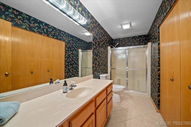 bathroom with tile patterned flooring, vanity, toilet, and walk in shower