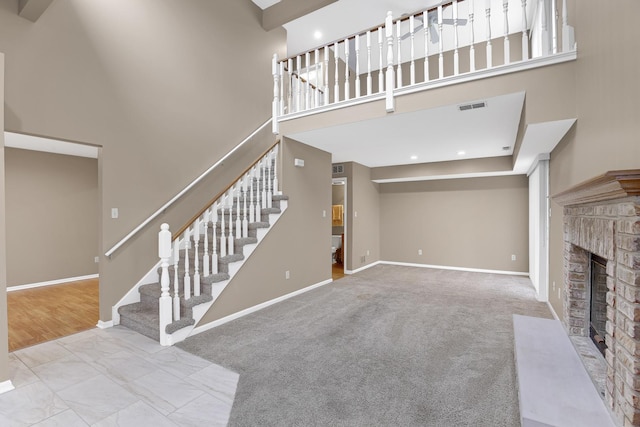 living room with a towering ceiling, light colored carpet, and a fireplace