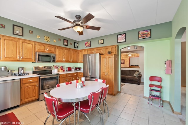 kitchen with light tile patterned flooring, ceiling fan, and stainless steel appliances