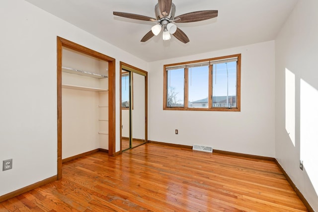 unfurnished bedroom with light hardwood / wood-style floors, ceiling fan, and two closets