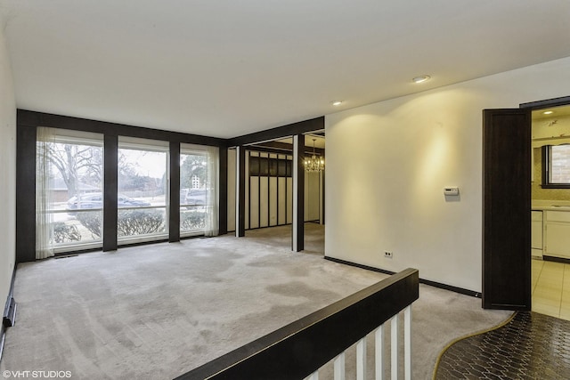 carpeted spare room featuring an inviting chandelier