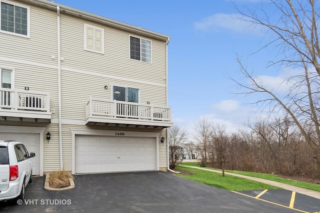 rear view of property with a garage and a balcony