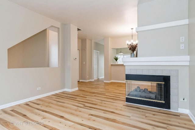 unfurnished living room with hardwood / wood-style flooring, a multi sided fireplace, and a chandelier