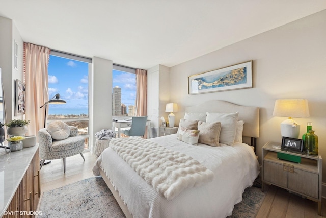 bedroom with floor to ceiling windows and light wood-type flooring