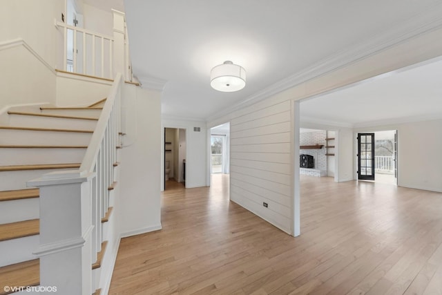 interior space with ornamental molding, a fireplace, and light wood-type flooring