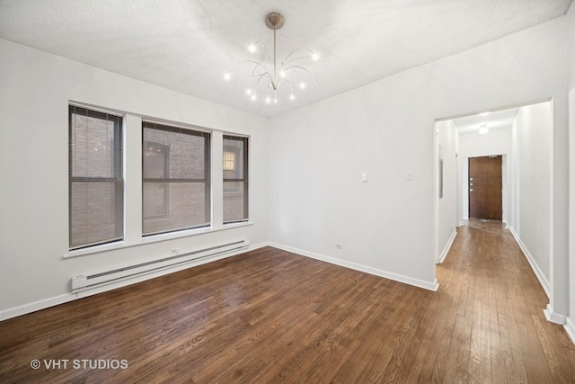 empty room with baseboards, a notable chandelier, a baseboard heating unit, and wood finished floors