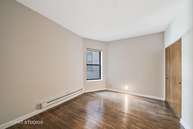 unfurnished room featuring a baseboard heating unit, dark wood-type flooring, a textured ceiling, and baseboards