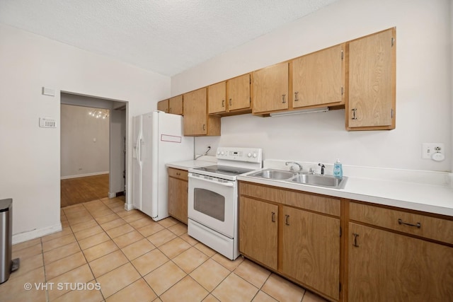 kitchen with light tile patterned floors, light countertops, a sink, a textured ceiling, and white appliances