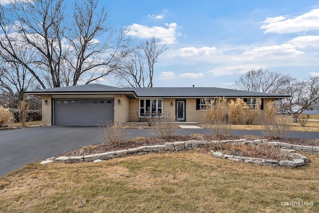 ranch-style house featuring a garage, brick siding, aphalt driveway, and a front yard