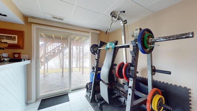 workout room featuring a paneled ceiling and light tile patterned floors