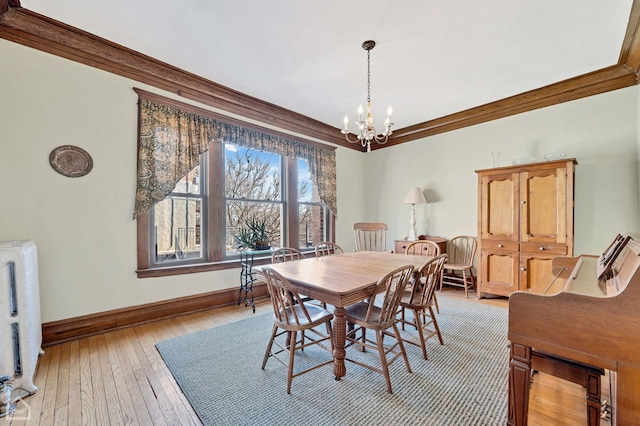 dining space with light hardwood / wood-style flooring, a notable chandelier, radiator heating unit, and ornamental molding