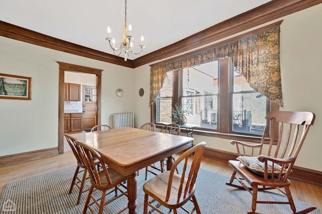 dining area with ornamental molding, a chandelier, radiator heating unit, and light wood-type flooring