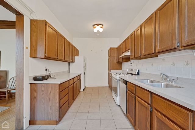 kitchen featuring light tile patterned flooring, sink, backsplash, and white appliances