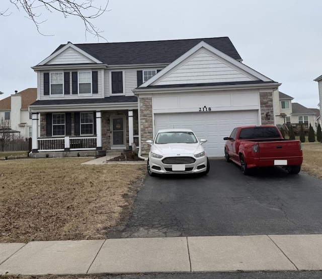 view of front of property with a porch, a garage, and a front lawn