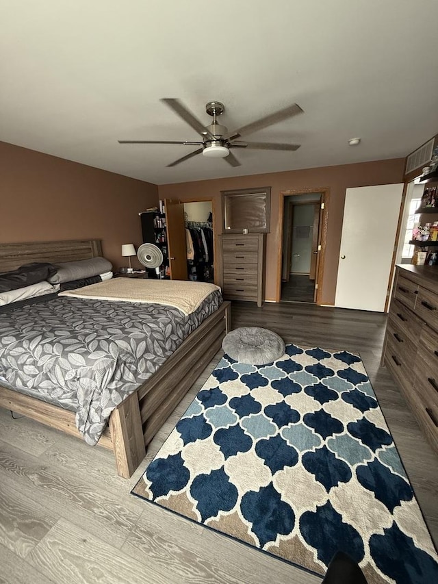 bedroom featuring hardwood / wood-style flooring, a spacious closet, ceiling fan, and a closet