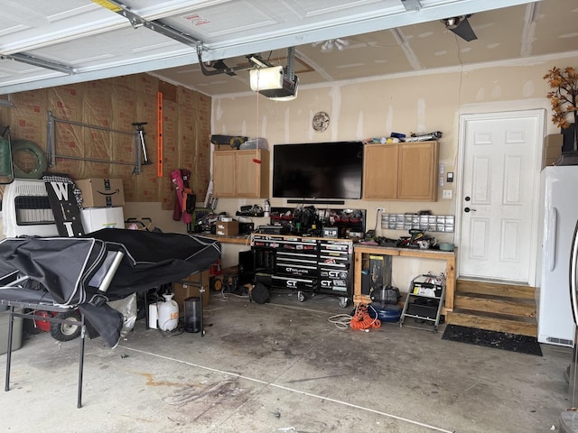 garage with fridge, a garage door opener, and a workshop area