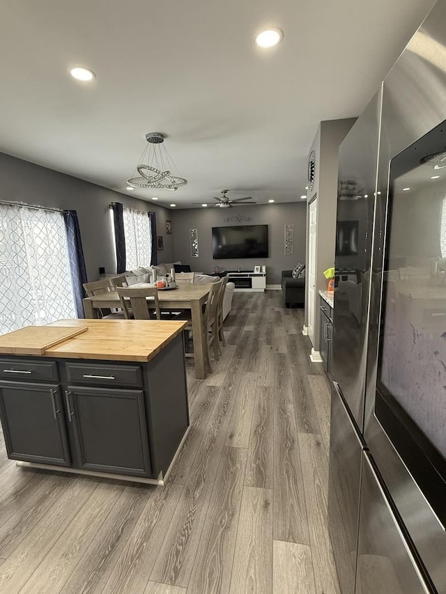 kitchen featuring pendant lighting, stainless steel fridge, ceiling fan, butcher block counters, and hardwood / wood-style floors