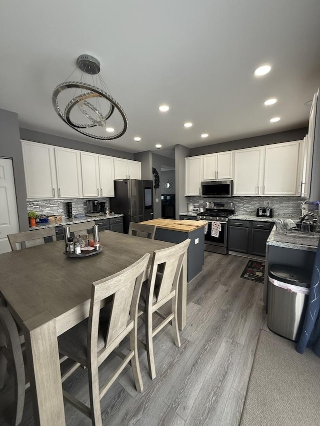 kitchen featuring wood counters, decorative light fixtures, stainless steel appliances, decorative backsplash, and white cabinets