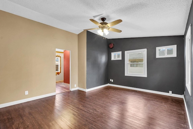 empty room with lofted ceiling, a textured ceiling, dark wood-type flooring, and ceiling fan