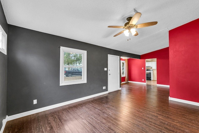 empty room with vaulted ceiling, dark wood-type flooring, a textured ceiling, and ceiling fan