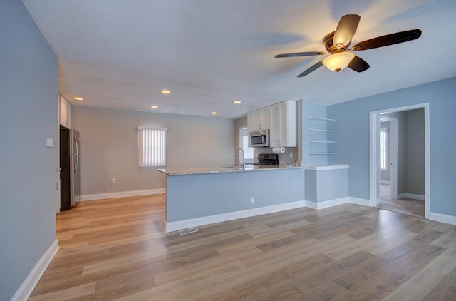 kitchen featuring white cabinets, appliances with stainless steel finishes, kitchen peninsula, and light wood-type flooring