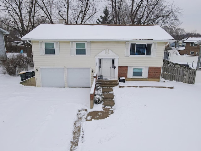 bi-level home with brick siding, fence, and an attached garage