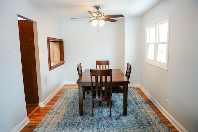 dining room with a ceiling fan, baseboards, and wood finished floors