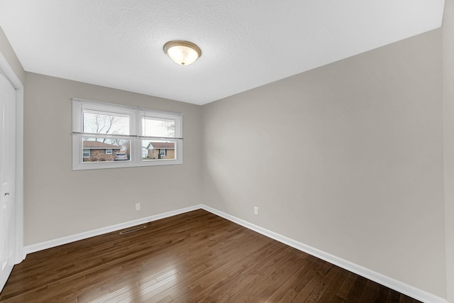 unfurnished room featuring dark wood-type flooring and a textured ceiling