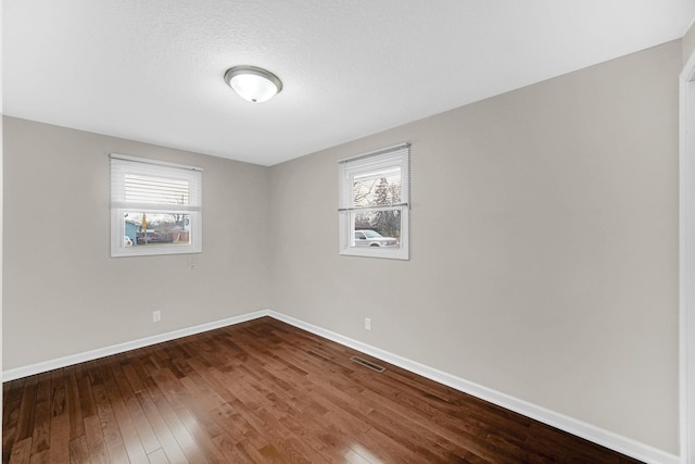 unfurnished room with plenty of natural light, dark wood-type flooring, and a textured ceiling