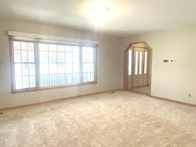 unfurnished room with light colored carpet and plenty of natural light