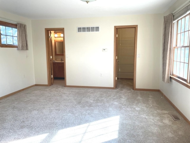 unfurnished bedroom featuring multiple windows, carpet, and ensuite bath