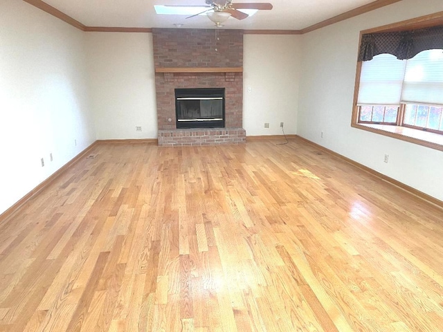 unfurnished living room with crown molding, a brick fireplace, ceiling fan, and light hardwood / wood-style flooring