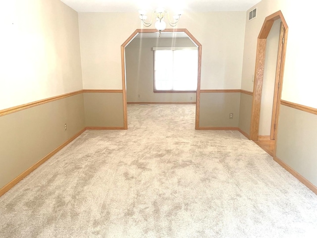 unfurnished room featuring light colored carpet and a chandelier