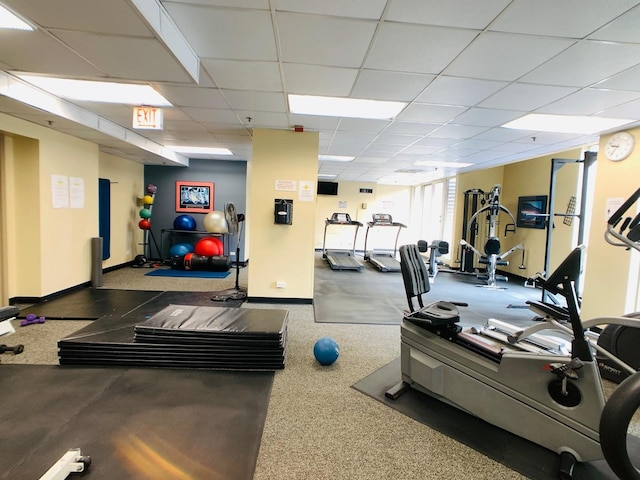 exercise room featuring a drop ceiling and baseboards