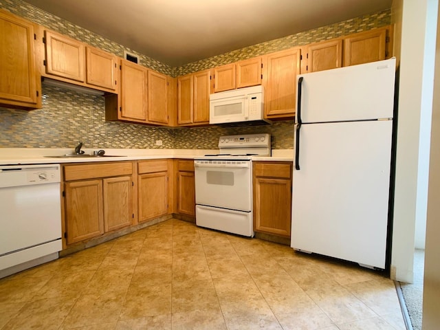 kitchen with white appliances, decorative backsplash, light countertops, and a sink