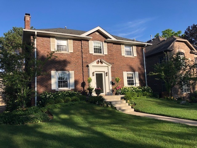 colonial-style house featuring a front yard