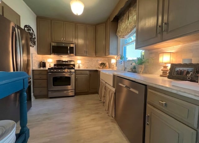 kitchen with sink, decorative backsplash, light hardwood / wood-style flooring, and stainless steel appliances