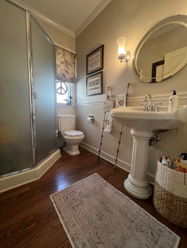 bathroom featuring hardwood / wood-style floors, a shower with shower door, ornamental molding, and toilet