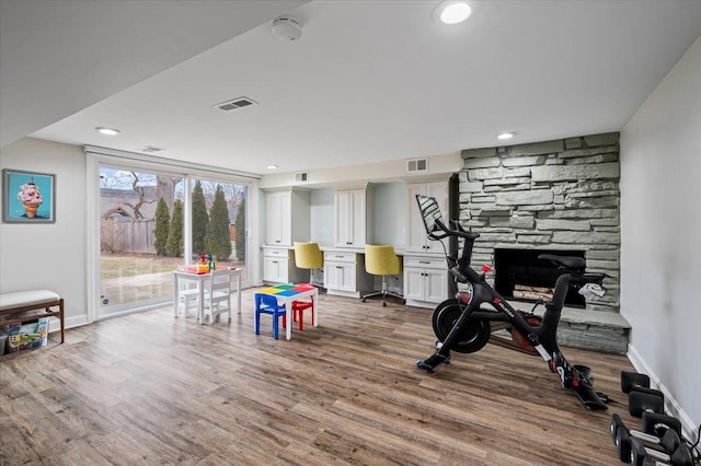 exercise room with a stone fireplace and hardwood / wood-style floors