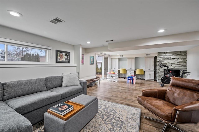 living room with hardwood / wood-style floors and a stone fireplace