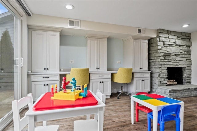 recreation room featuring a fireplace, built in desk, and wood-type flooring