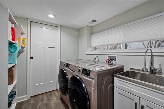 laundry room featuring dark wood-type flooring, cabinets, sink, and washing machine and clothes dryer