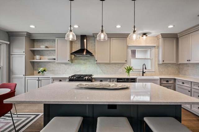 kitchen featuring wall chimney range hood, gray cabinets, and range with gas stovetop