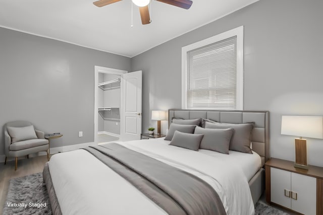 bedroom featuring hardwood / wood-style flooring, a walk in closet, and ceiling fan