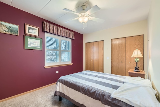 carpeted bedroom featuring multiple closets and ceiling fan